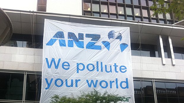 Protesters hang a sign on the ANZ bank on the corner of Creek and Queen streets in Brisbane's CBD this morning.