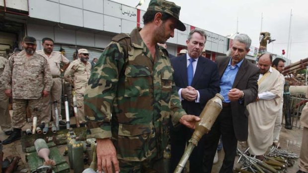An anti-Gaddafi fighter shows off captured weapons to British Defence Secretary Liam Fox during a visit to Misrata, 200 kilometres outside Tripoli, at the weekend.