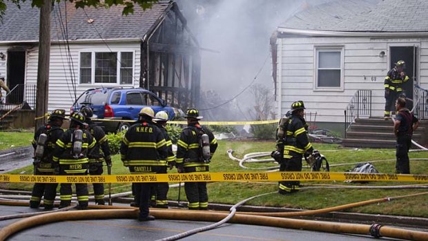 Fire and rescue personnel surround the site where a plane crashed into a house in East Haven, Connecticut.