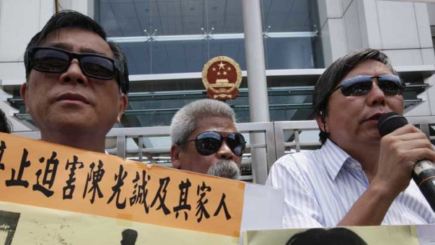 Protesters in Hong Kong hold placards picturing activist Chen Guangcheng (third from left) with his family, and activist He Peirong (right).