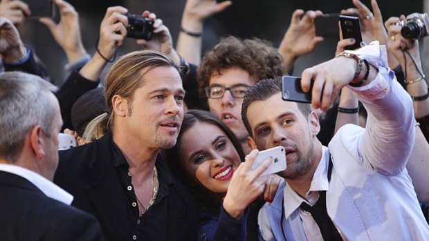 Brad Pitt pauses to take a picture with fans on the red carpet.