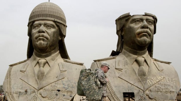US Army soldiers stroll past two bronze busts of former Iraqi president Saddam Hussein in the Green Zone in Baghdad.