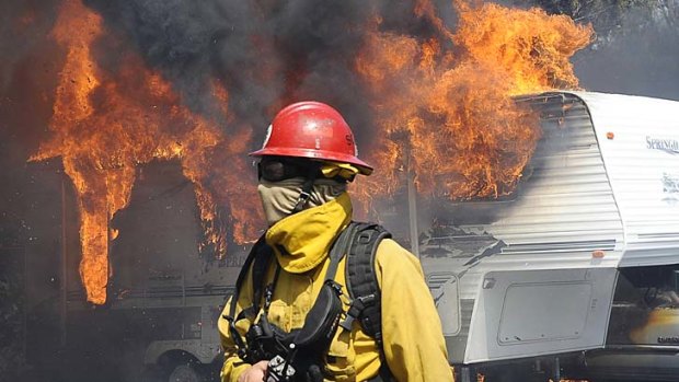 Firefighters work as the wildfire destroys trailers and motorhomes near LA.