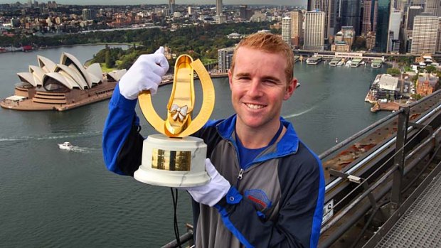 Jockey Tommy Berry poses on the Sydney Harbour Bridge with the Golden Slipper trophy on Friday. Berry will ride the Gai Waterhouse-trained favourite, Overreach, in the race.