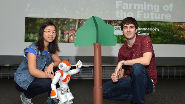 Student Eva Wang and QUT lecturer Christopher Lehnert with a robot designed to pick fruit. 
