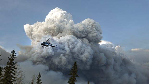 A helicopter flies past a wildfire in Fort McMurray, Alberta on Wednesday.