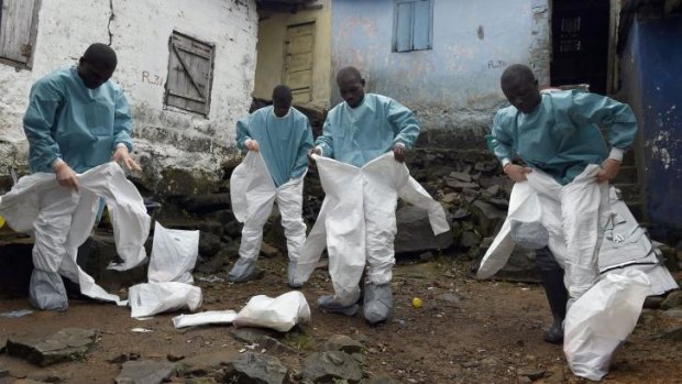 Medical staff members of the Croix Rouge NGO put on protective suits before collecting the corpse of a victim of Ebola, in Monrovia.