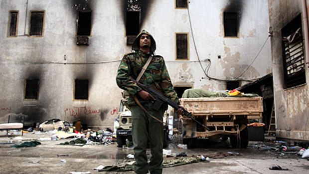 An opposition militiaman stands guard in front of the charred national security building in Libya’s second city, Benghazi.