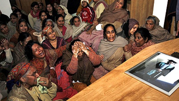 Nitin Garg's distraught mother, Praveen Kumari Garg, covers her head in anguish beside her son's coffin, surrounded by wailing relatives. The dead 21-year-old's graduation photograph is on the lid of the coffin.