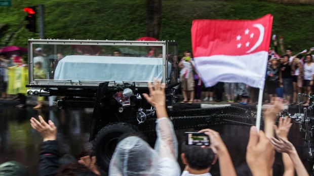 Mourners wave as a gun carriage bearing the coffin of Singapore's first elected prime minister, Lee Kuan Yew, travels towards the University Cultural Centre at the National University of Singapore during his funeral procession.