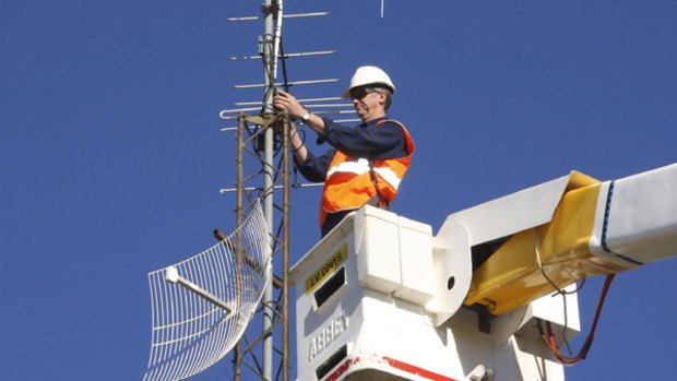 Mark Wilson stands in a cherry picker to adjust TV antennas on a mast.
