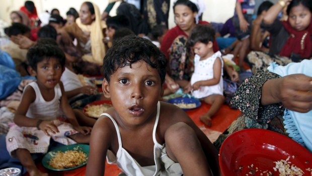 A young Rohingya migrant, who arrived in Indonesia today by boat with other Rohingya and Bangladeshi migrants, eats inside a temporary shelter at Kuala Langsa in Indonesia's Aceh Province.
