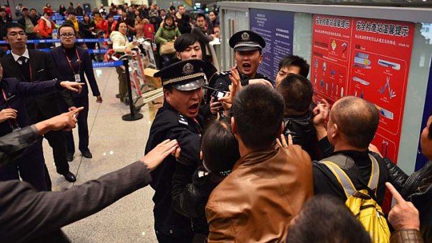 Stranded travellers argue with police and airline personnel at Changshui International Airport.