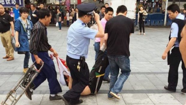 A man, whom local media say is a suspect, is detained after a knife attack at a railway station in Guangzhou on Tuesday. 