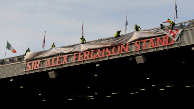 Workmen reveal the sign for the Sir Alex Ferguson Stand.