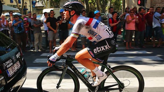Battered and bruised: Mark Cavendish rides with a ripped shirt after falling off his bike.