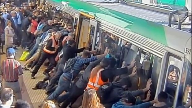 Strength in unity: Perth commuters push against a train to free a passenger’s trapped leg.