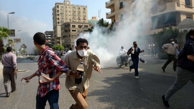Egyptian Muslim Brotherhood supporters run from tear gas fired by Egyptian police.