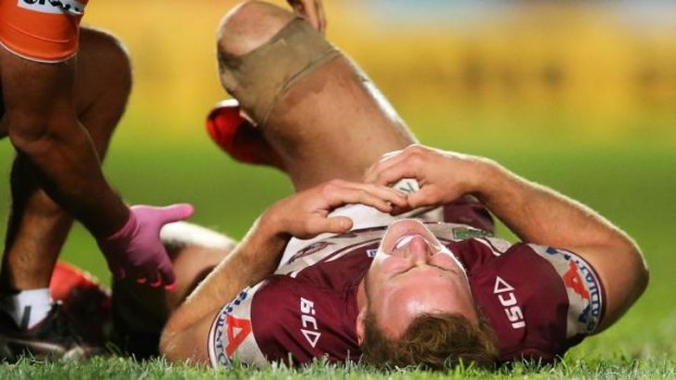 Daly Cherry-Evans of the Sea Eagles receives attention from a trainer after a tackle by Sam Kasiano.