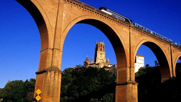 A fast train crosses a bridge by Albi Cathedral, France.