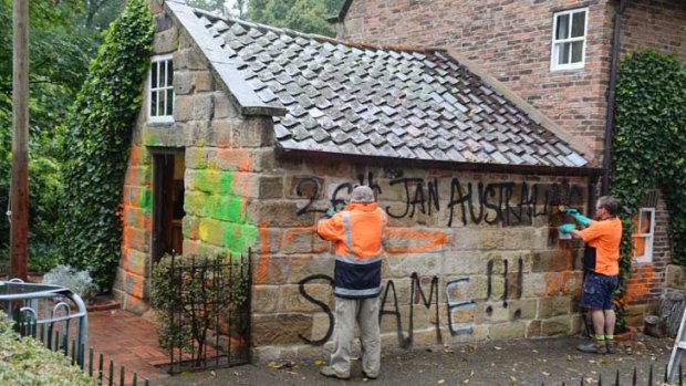 Workers clean graffiti at Captain Cook's cottage.