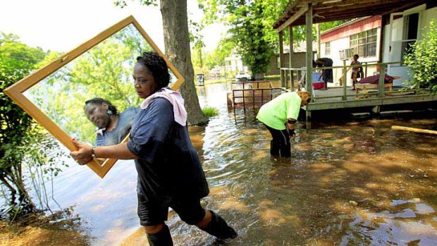 Melvina Jones carries a mirror through flood waters as the swelling Mississippi River surrounds her sister's home in Vicksburg, Mississippi.