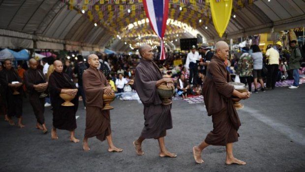 Buddhist monks stroll through an ongoing demonstration by anti-government protesters outside Government House in Bangkok.