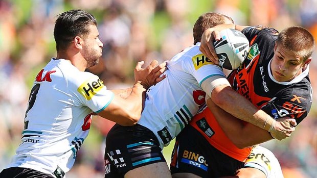 Persistence pays off: Wests Tigers' Blake Ayshford is tackled by a pair of Panthers in Sunday's game at Campbelltown.