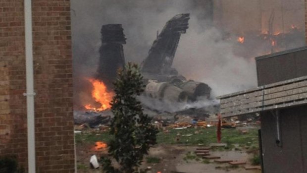 The burning fuselage of US Navy jet lies smoldering after crashing into a residential building.