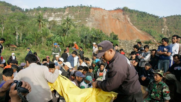 Grim task ... rescue workers remove a body from debris in Cirangkareng village, West Java, where a landslide buried homes and a games arcade full of children.