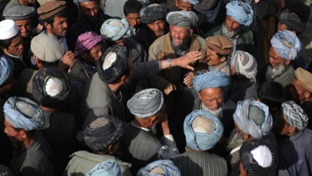 Landslide-affected Afghan villagers gather to receive donated supplies.