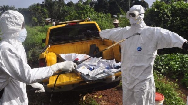 A health worker sprays disinfectant onto a colleague after they buried an Ebola victim on the outskirts of  Monrovia, Liberia.