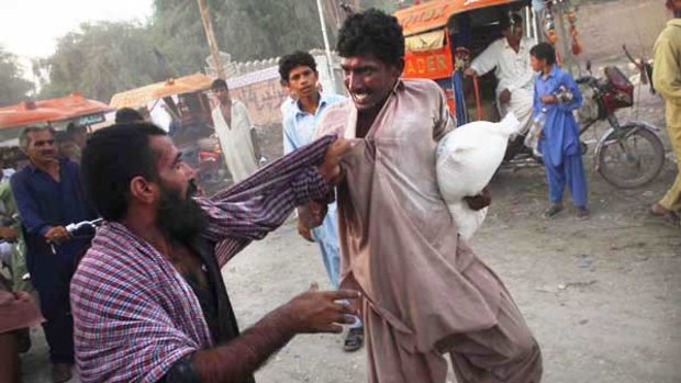 Pakistanis displaced by flooding fight over a bag of flour.