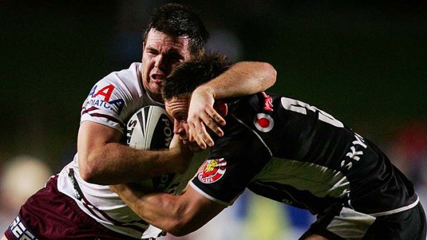 Jamie Lyon of Manly is tackled by Shaun Berrigan of the Warriors.