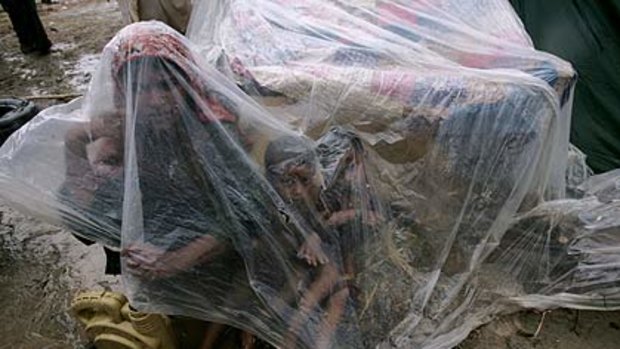 A family huddle under plastic as they wait for help to evacuate to safety along a road in Shekarpur, Pakistan.