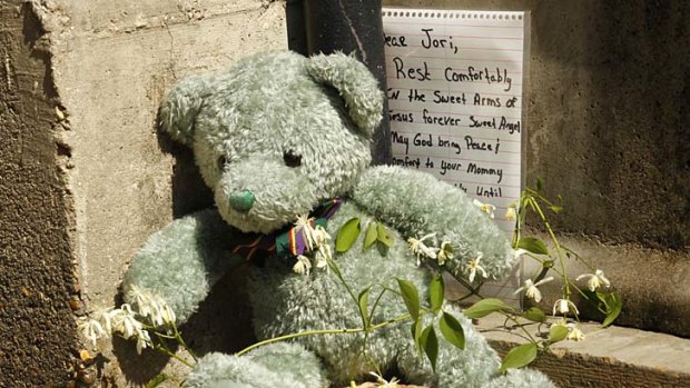 Horrific death ... a stuffed bear and a handwritten note are seen outside the home where Jori Lirette was found decapitated.