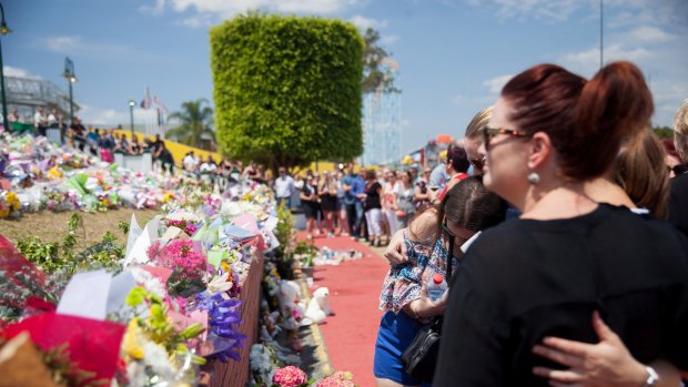 Dreamworld staff in front of flowers placed as tribute to four people who died after an industrial accident on Tuesday. 