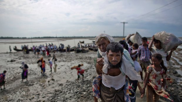 Rohingya Muslim man from Myanmar carries an elderly woman after they crossed the border into Bangladesh from Myanmar. 