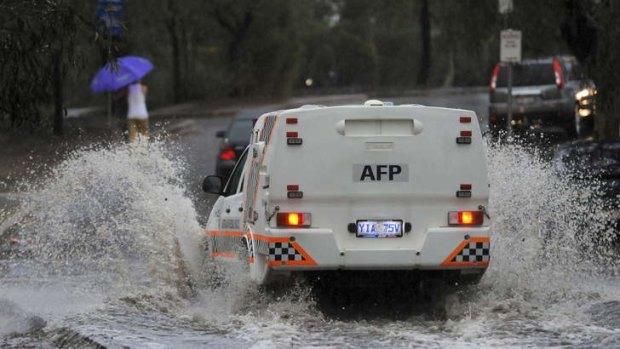 A police car makes it way through a flooded street.