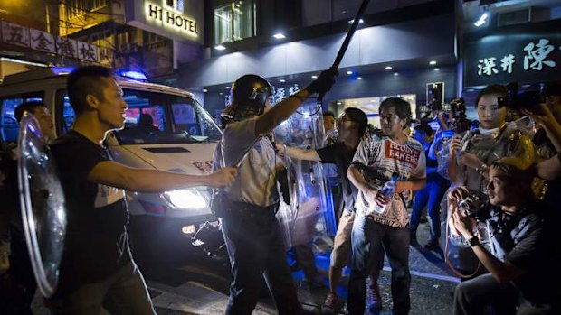 A riot police officer holds a baton as he confronts Occupy Central protesters.