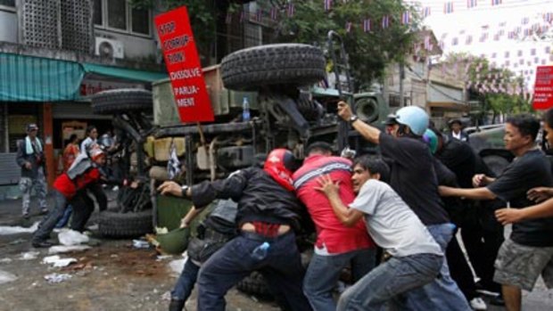 Uneasy peace... anti-government protesters manhandle an abandoned armoured vehicle after riots in central Bangkok.