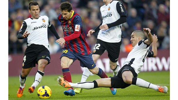 Barcelona's Lionel Messi (centre) attempts to dribble past Valencia's Juan Bernat (left) and Oriol Romeu (right).
