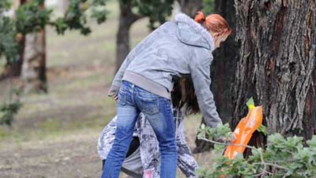 Young women place flowers at the crash scene. PHOTO Pat Scala