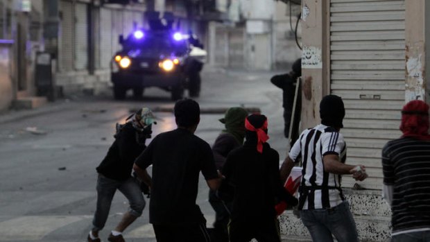 Anti-government protesters throw stones at armoured vehicles in Sanabis, on the edge of the capital Manama.
