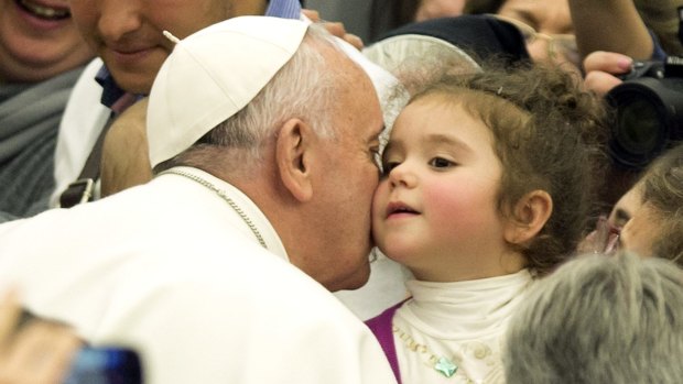 Pope Francis kisses a baby at the Vatican on Saturday.