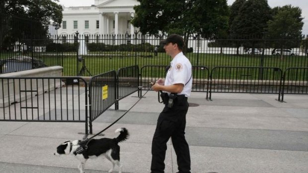 A US Secret Service Uniformed Division officer and his bomb-sniffing dog walk along the north fence of the White House.