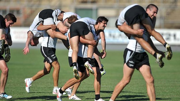 Changing the pace: Magpies Darren Jolly and Scott Pendlebury carry a teammate each during a pre-season training race.