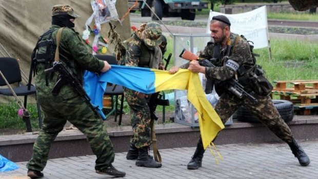 Separatist fighters tear apart a Ukrainian flag outside the regional government headquarters in Donetsk, eastern Ukraine, on Thursday.
