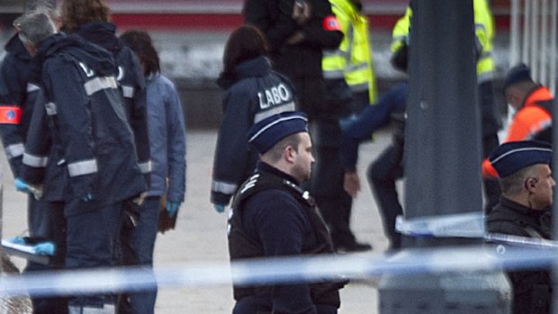 Police stand next to evidence markers after a gunman fired guns and grenades at Christmas crowds in Liege, Belgium.