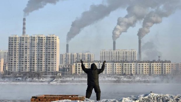 Big issue: A man exercises in the morning as he faces chimneys emitting smoke across the Songhua river in Jilin, northern China.
